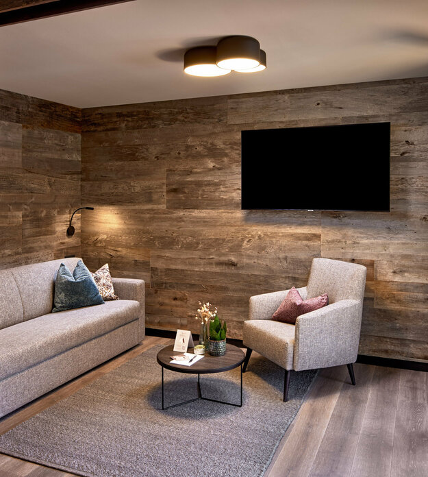 Abtrennbarer Wohnbereich mit Sofa, Sessel, Fernseher und Balkonzugang im Mei.Rückzug Appartement