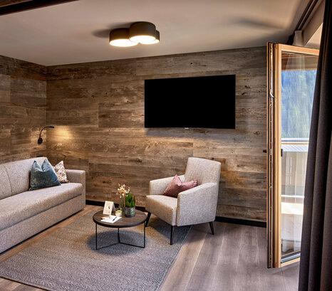 Abtrennbarer Wohnbereich mit Sofa, Sessel, Fernseher und Balkonzugang im Mei.Rückzug Appartement