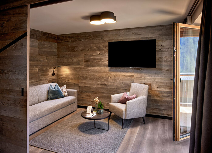 Abtrennbarer Wohnbereich mit Sofa, Sessel, Fernseher und Balkonzugang im Mei.Rückzug Appartement