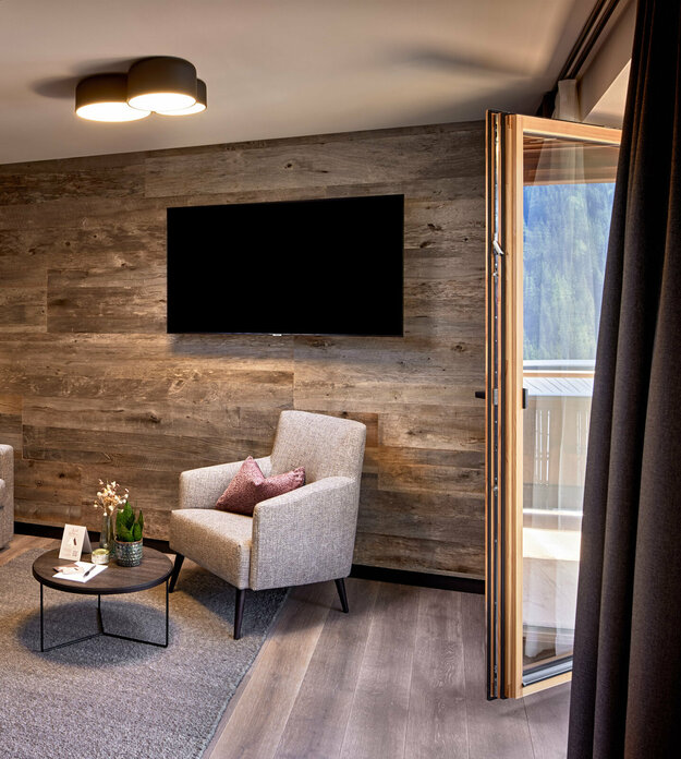 Abtrennbarer Wohnbereich mit Sofa, Sessel, Fernseher und Balkonzugang im Mei.Rückzug Appartement