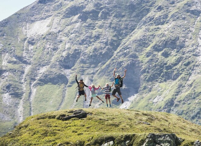 Familie macht einen Lufstsprung vor Gipfelpanorama