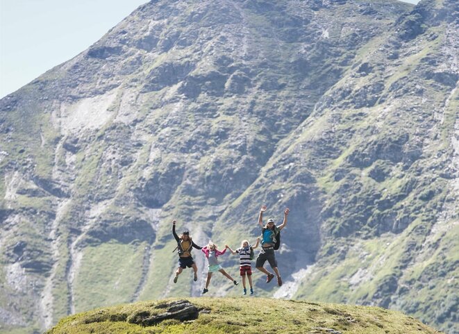 Familie macht einen Lufstsprung vor Gipfelpanorama