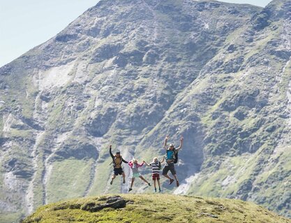 Familie macht einen Lufstsprung vor Gipfelpanorama