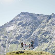 Familie macht einen Lufstsprung vor Gipfelpanorama