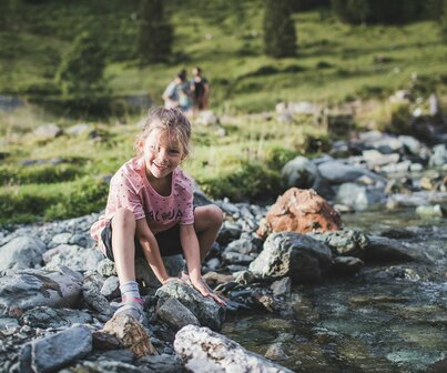 Mädchen spielt an einem Gebirgsbach