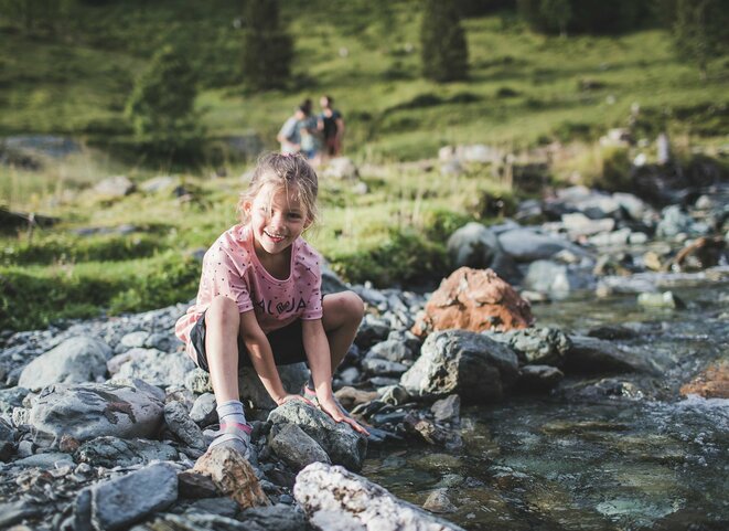 Mädchen spielt an einem Gebirgsbach