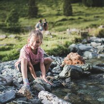 Mädchen spielt an einem Gebirgsbach