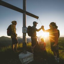 Wandergruppe bei Sonnenaufgang am Gipfelkreuz