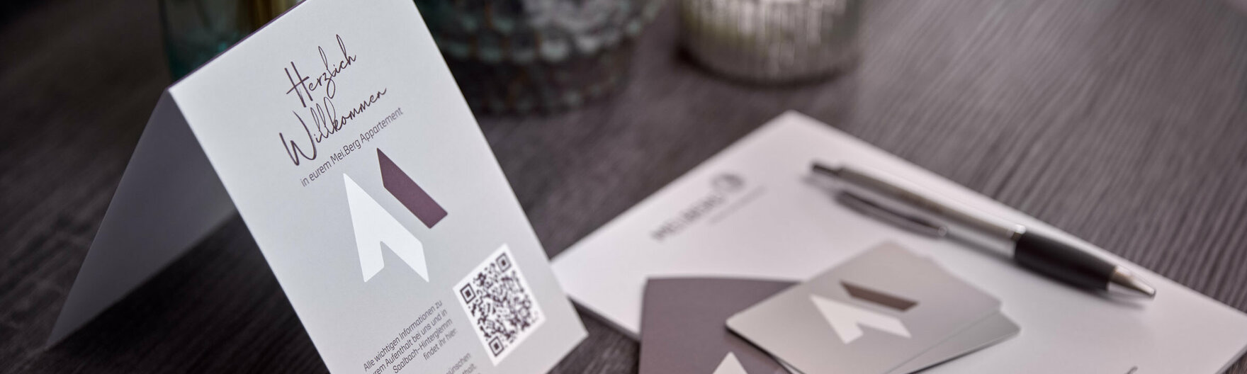 Mei.Berg Infomaterial auf Wohnzimmertisch mit Blumen