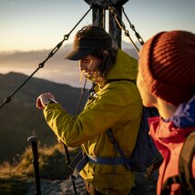Zwei Wanderer bei Sonnenaufgang am Gipfelkreuz