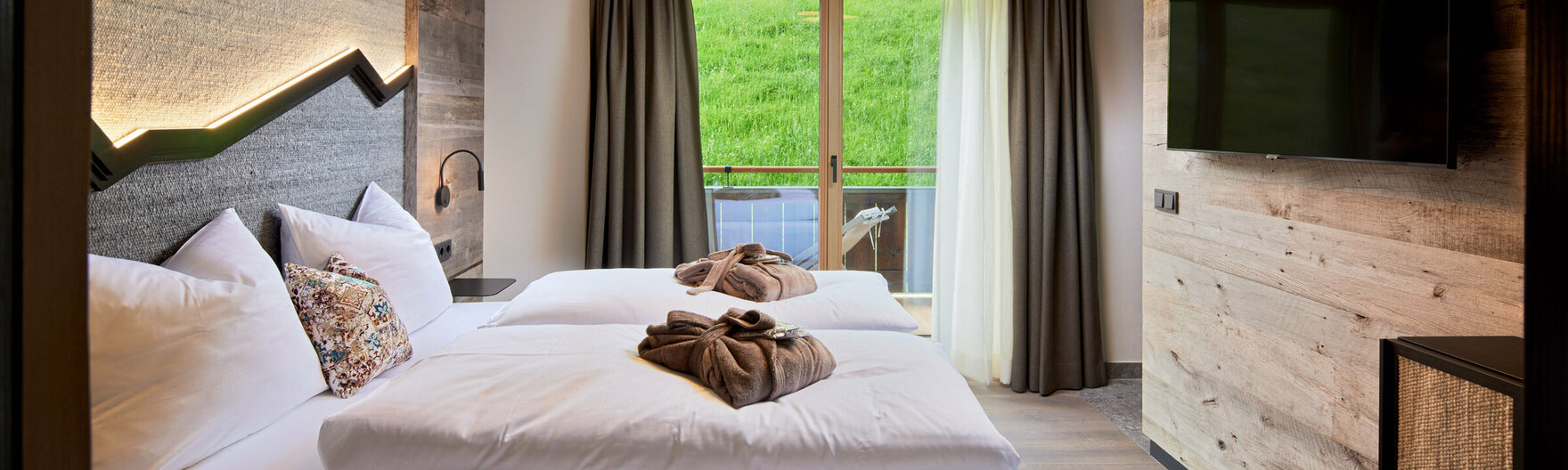 Schlafzimmer mit Doppelbett, Fernseher und Balkonzugang im Mei.Auszeit Appartement