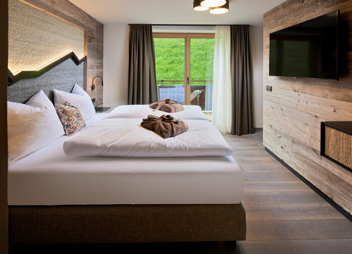 Schlafzimmer mit Doppelbett, Fernseher und Balkonzugang im Mei.Auszeit Appartement