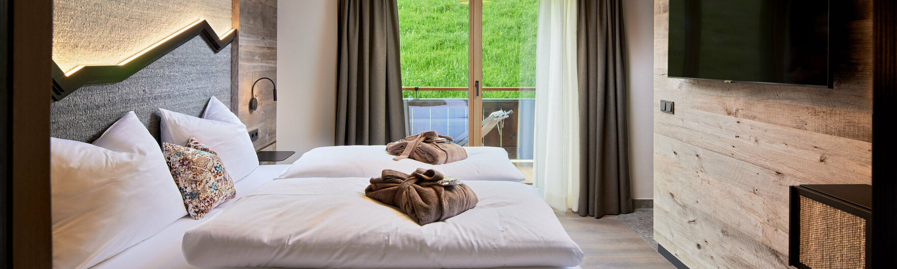 Schlafzimmer mit Doppelbett, Fernseher und Balkonzugang im Mei.Auszeit Appartement