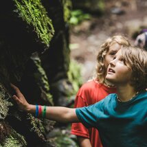 Zwei Kinder berühren moosige Felsen