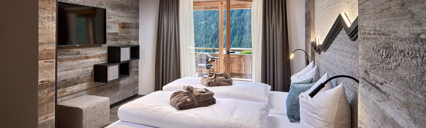 Schlafzimmer mit Doppelbett, Fernseher und offener Balkontür im Mei.Rückzug Appartement