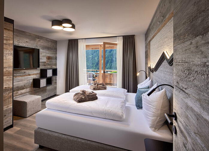 Schlafzimmer mit Doppelbett, Fernseher und offener Balkontür im Mei.Rückzug Appartement