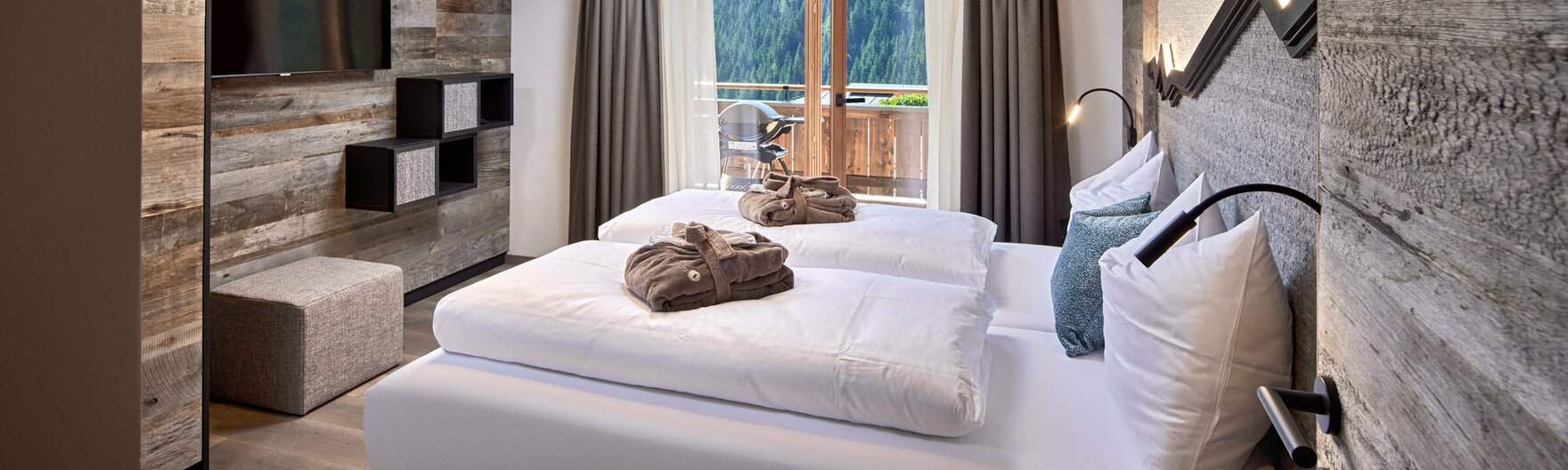 Schlafzimmer mit Doppelbett, Fernseher und offener Balkontür im Mei.Rückzug Appartement