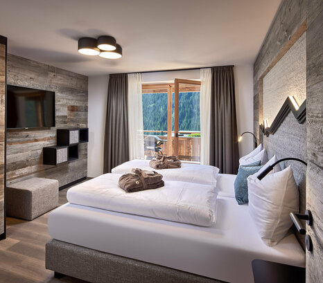 Schlafzimmer mit Doppelbett, Fernseher und offener Balkontür im Mei.Rückzug Appartement