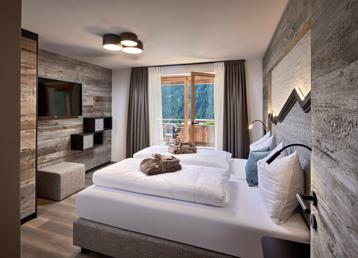 Schlafzimmer mit Doppelbett, Fernseher und offener Balkontür im Mei.Rückzug Appartement