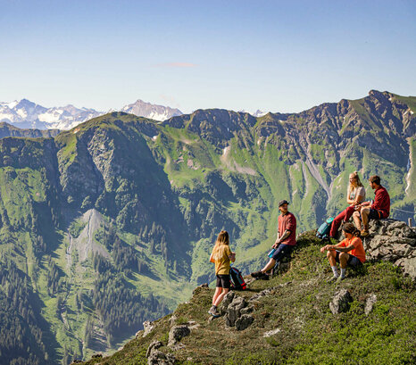 Wandergruppe bei Rast vor Gebirgspanorama