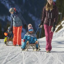 Kinder werden auf Rodeln den Berg hochgezogen