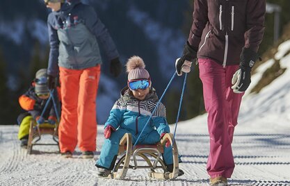 Kinder werden auf Rodeln den Berg hochgezogen