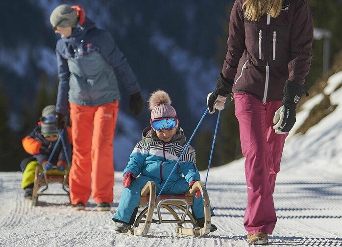 Kinder werden auf Rodeln den Berg hochgezogen