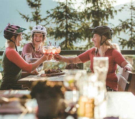 Drei Frauen in Mountainbikeausrüstung machen Rast auf der Alm