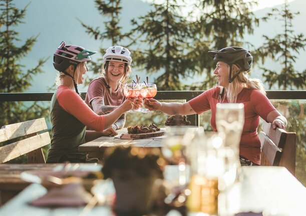 Drei Frauen in Mountainbikeausrüstung machen Rast auf der Alm