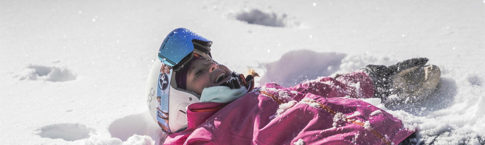 Kind mit Skiausrüstung liegt im Schnee