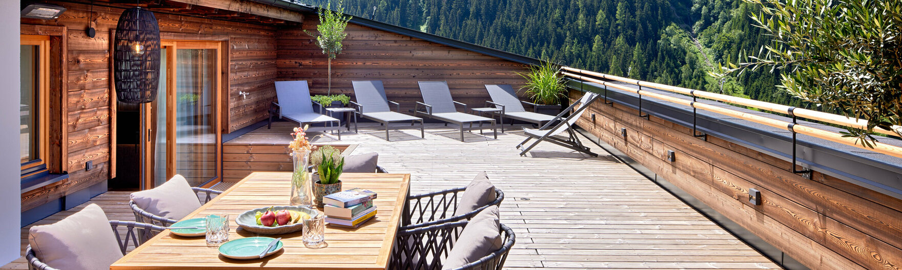 Dachterrasse mit großem Esstisch, Sonnenliegen und Ausblick auf Berge