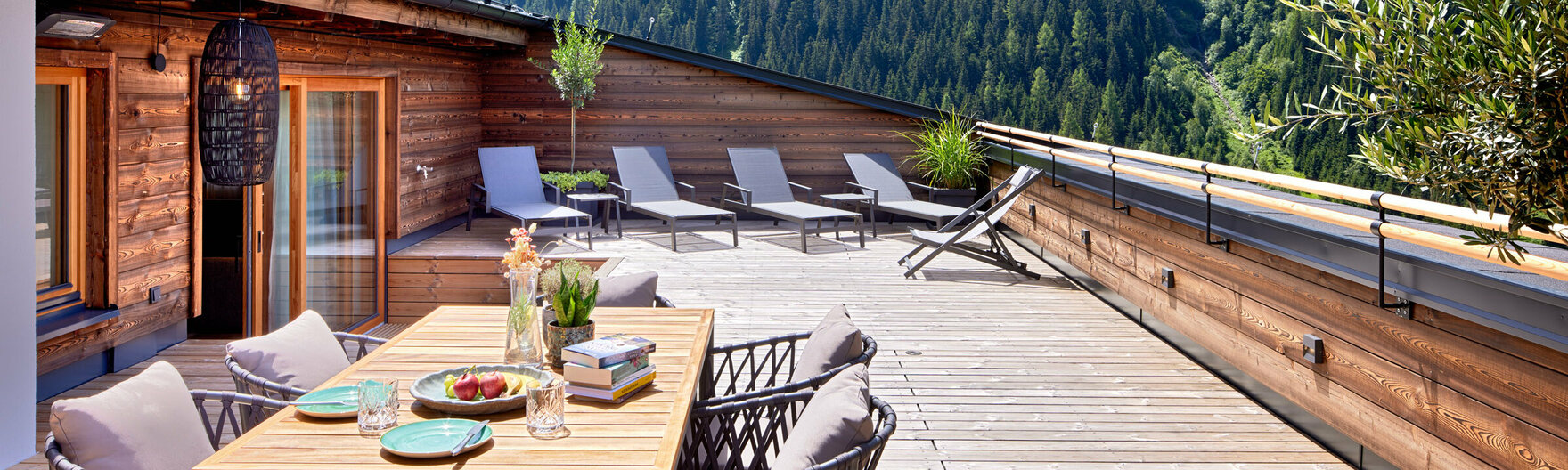 Dachterrasse mit großem Esstisch, Sonnenliegen und Ausblick auf Berge