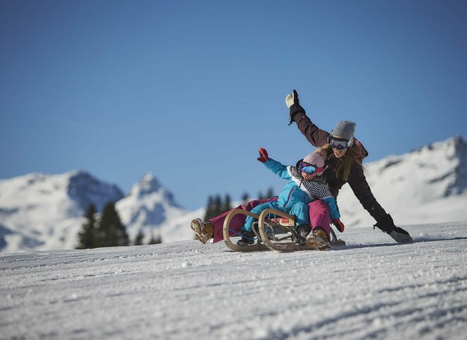 Frau mit Kleinkind beim Rodeln