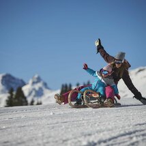 Frau mit Kleinkind beim Rodeln