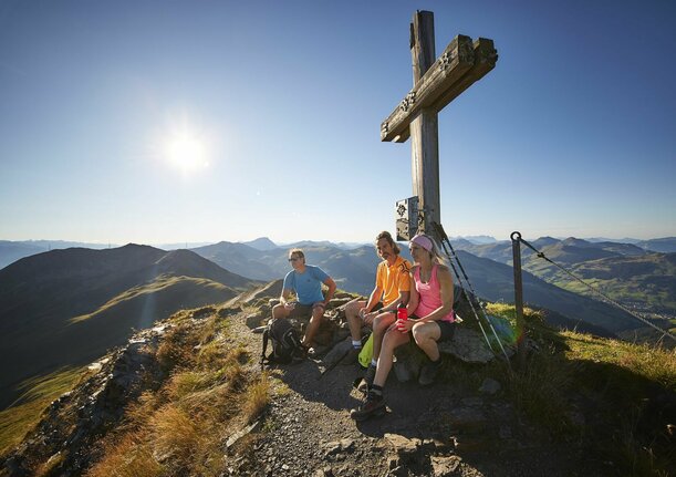 Wandergruppe macht Rast am Gipfelkreuz